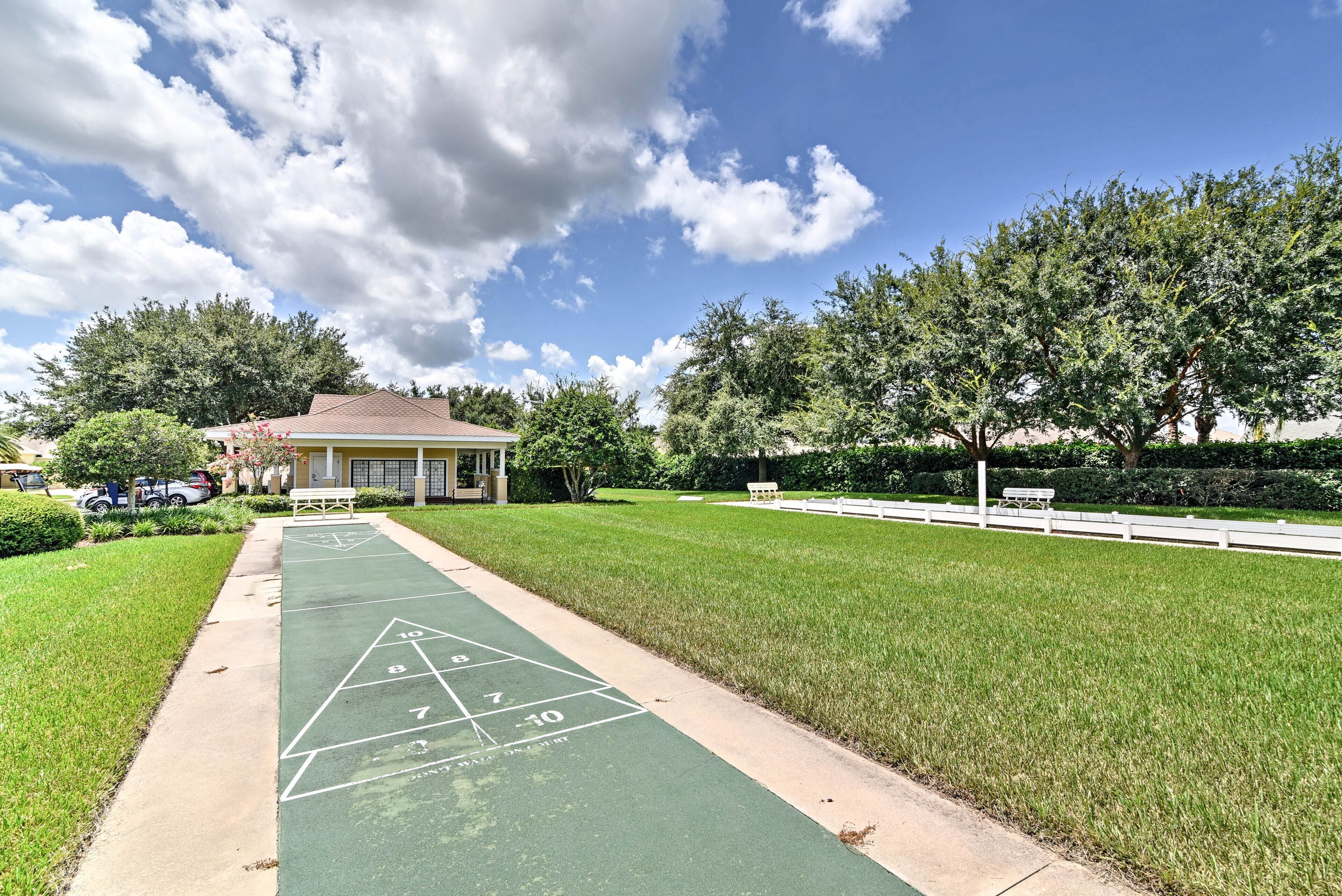 A green shuffleboard court with a house in the background.
