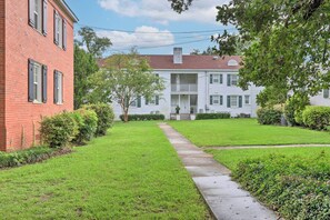 A two-story brick building with a front porch and a well-maintained lawn. - Cozy Mobile Condo w/ Community Outdoor Pool! (Mobile)