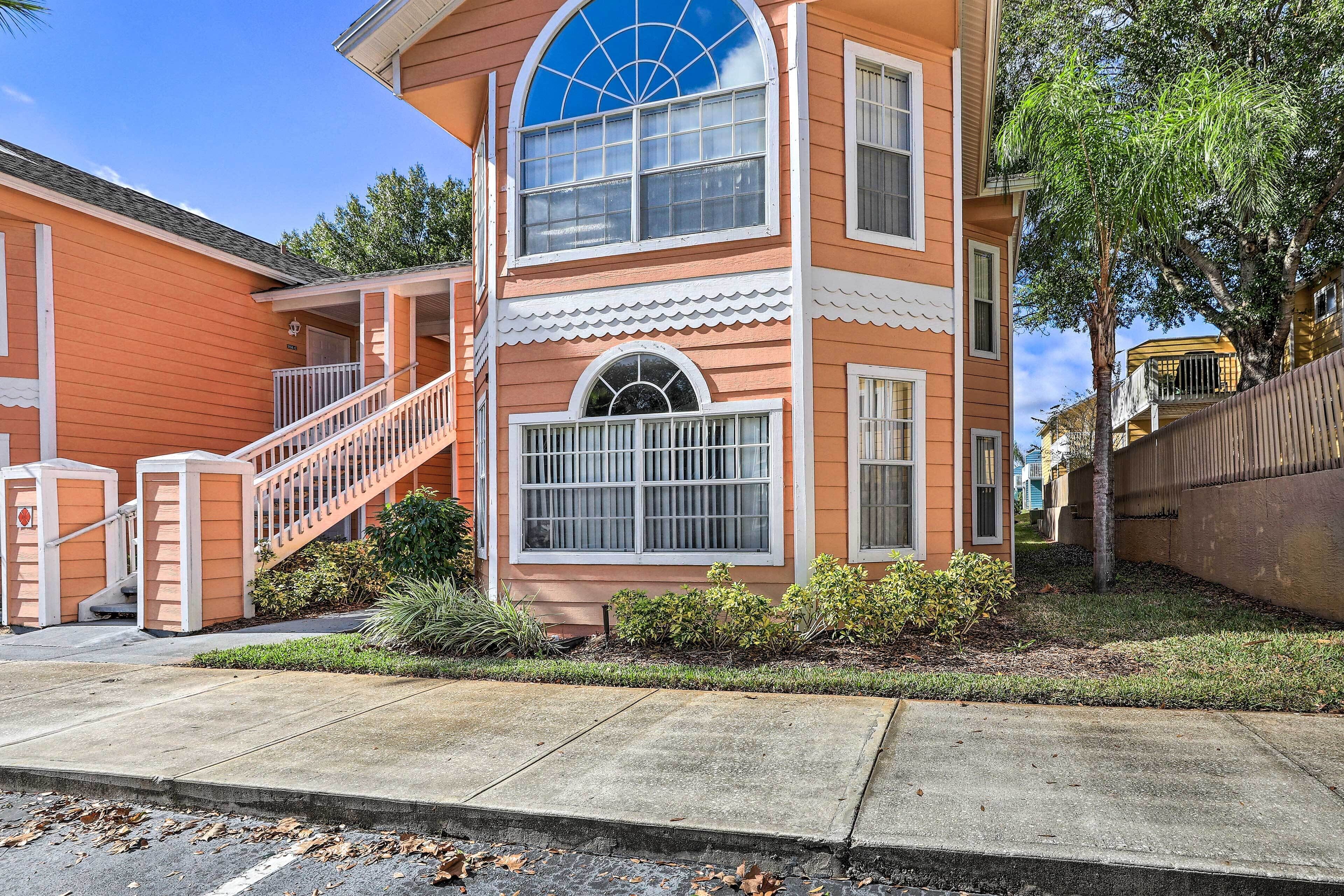 A two-story building with a porch, a staircase, and a large arched window.