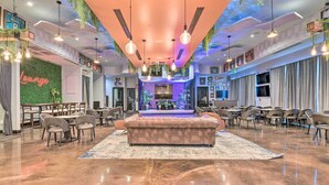 A spacious lounge area with a central seating area, multiple tables, and chairs. - Modern Resort Condo With Balcony - Walk to Beach! (Destin)