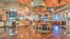 A spacious lobby with a polished concrete floor, a central seating area with a round table and chairs, and a coffee bar with a menu board. - Modern Resort Condo With Balcony - Walk to Beach! (Destin)