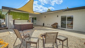 Un patio exterior moderno con jacuzzi, zona de estar y un amplio ventanal.