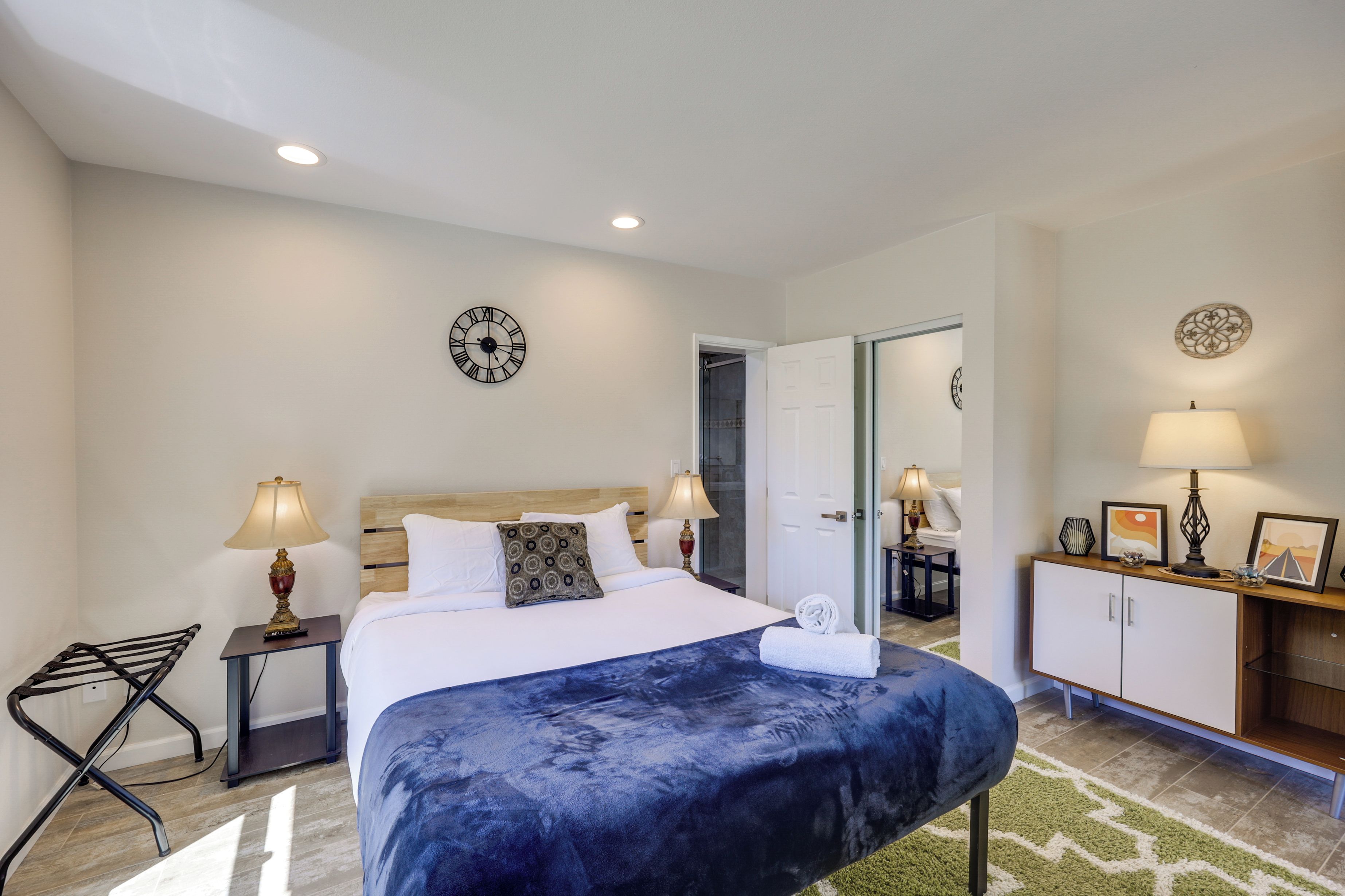 A hotel room with a bed, a desk, a chair, a wardrobe, and a door leading to another room.