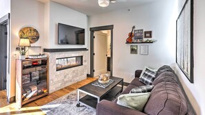 A modern living room with a fireplace, a flat-screen TV, a sofa, and a coffee table. - Modern Mountain Getaway, Walk to Grand Lake! (Grand Lake)