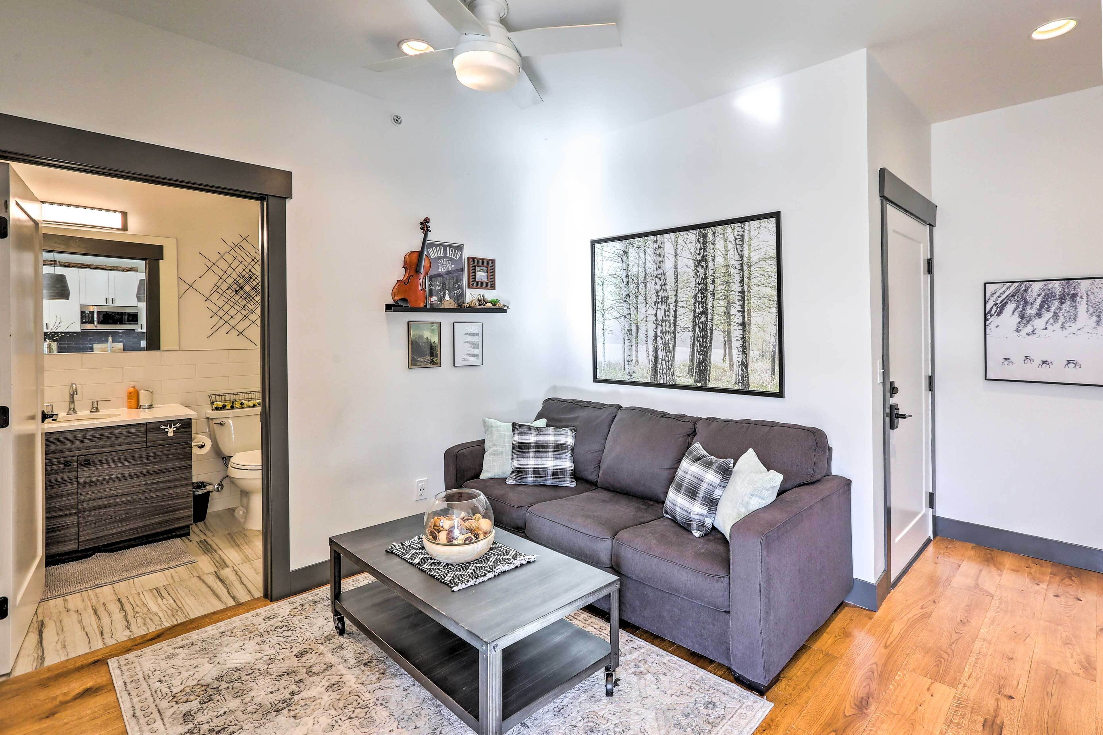 A modern living room with a grey sofa, a coffee table with a decorative bowl, and a large framed picture on the wall.