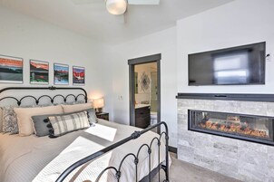 A bedroom with a bed, a fireplace, a TV, and framed pictures on the wall.
