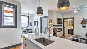 A modern kitchen with a large island, pendant lights, and a fireplace. - Modern Mountain Getaway, Walk to Grand Lake! (Grand Lake)
