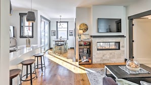 A modern kitchen with a bar area, a fireplace, and a dining area with natural light. - Modern Mountain Getaway, Walk to Grand Lake! (Grand Lake)