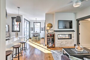 A modern kitchen with a bar area, a fireplace, and a dining area with natural light.