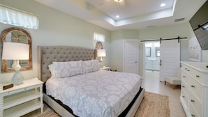 A bedroom with a large bed, two bedside tables with lamps, a ceiling fan, a wardrobe, and a door leading to a bathroom. - West End Home w/ Yard < 1 Mi to Beach Access! (Panama City Beach)