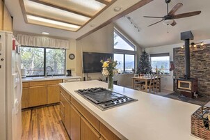 Una cocina moderna con una isla grande, armarios de madera, estufa integrada y una pared de acento de piedra.