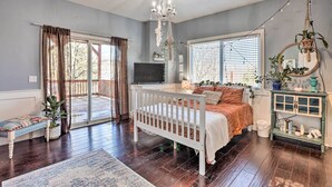 Une chambre avec un berceau blanc, une télévision, une grande fenêtre et un balcon.