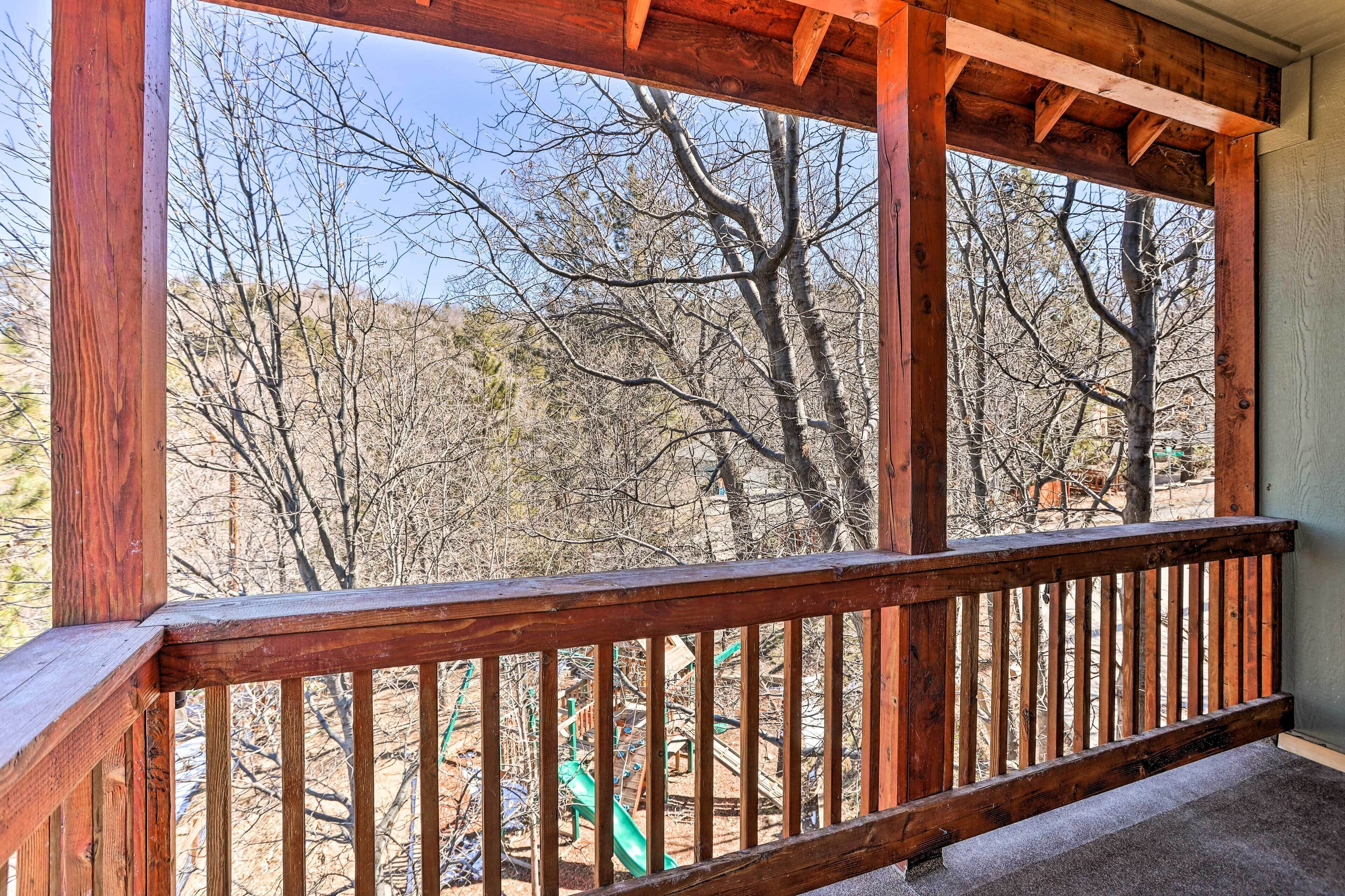 Ein Holzbalkon mit Blick auf einen Spielplatz und Bäume.