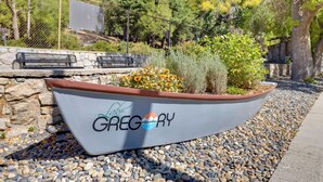 A boat-shaped planter with the text "Gregory" and a logo, surrounded by pebbles and plants. - Lake & Mountain-view Home: Walk to Downtown! (Crestline)