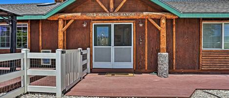 A rustic building with a wooden facade, a green roof, and a sign that reads 'GOLD MOUNTAIN RANCH'.