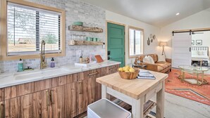 A kitchen with a large window, wooden cabinets, and a countertop with a sink. - Modern Joshua Tree Bungalow With Fire Pit & Bbq! (Joshua Tree)