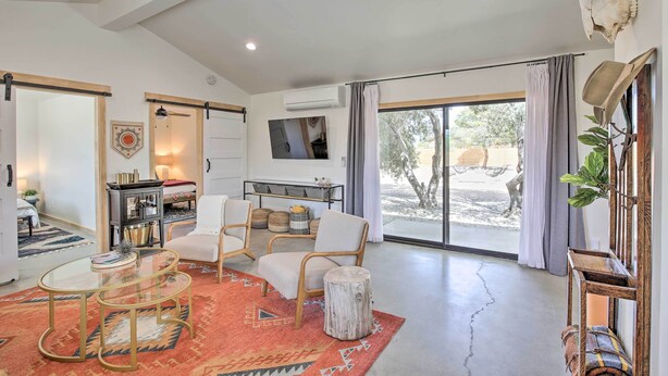 A spacious living room with a large window, a flat-screen TV, and a cozy seating area with a coffee table and chairs. - Modern Joshua Tree Bungalow With Fire Pit & Bbq! (Joshua Tree)