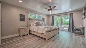 Une chambre à coucher avec un lit en bois, une table de chevet, un bureau avec une chaise et une grande fenêtre donnant sur un paysage verdoyant.