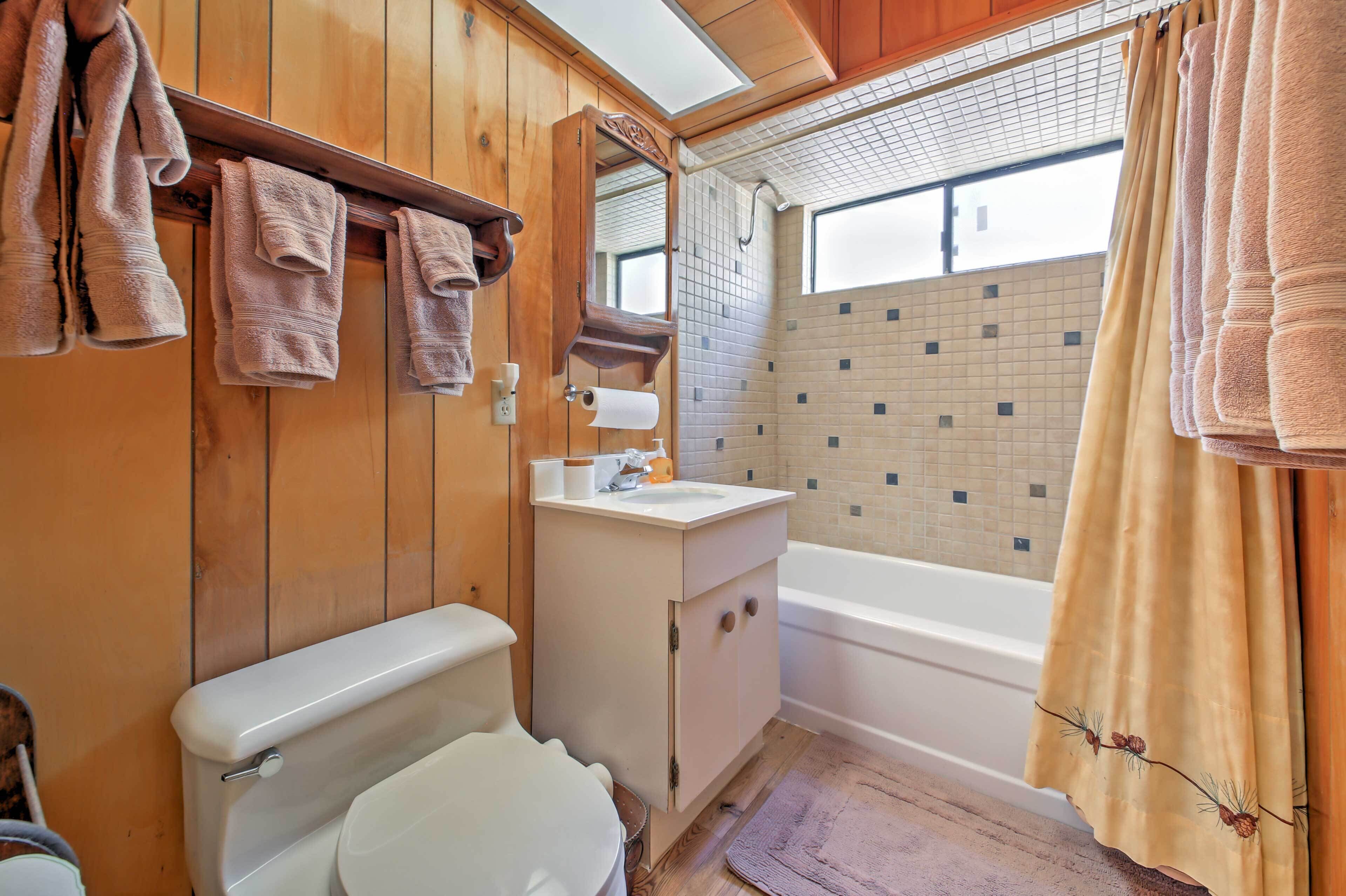 A bathroom with wooden walls, a toilet, a sink, and a bathtub.