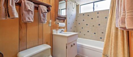 A bathroom with wooden walls, a toilet, a sink, and a bathtub.