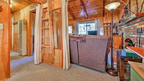 A wooden cabin interior with a kitchen area, a ladder, and a window. - Big Bear Lake Cabin w/ Deck ~ 7 Mi to Ski Slopes! (Fawnskin)
