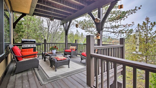 A covered outdoor deck with wicker furniture, a grill, and bird feeders. - Luxe Lake Arrowhead Home w/ Deck, 3 Mi to Village! (Lake Arrowhead)