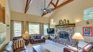 A spacious living room with a stone fireplace, leather sofas, and a flat-screen TV. - Luxe Lake Arrowhead Home w/ Deck, 3 Mi to Village! (Lake Arrowhead)