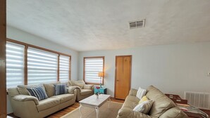 A living room with two beige sofas, a small white table, and a wooden floor. - IslandSeabreeze-Steps to Beach+1 Night Stays+Great for Cruisers/Families/Couples (Galveston)