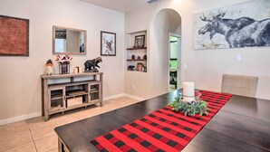 A dining area with a long table, a red and black checkered runner, and a moose painting on the wall. - 5 Mi to Big Bear Lake: Cozy Cottage w/ Hot Tub (Big Bear City)