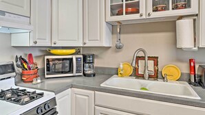 A kitchen with white cabinets, a stove, a microwave, a coffee maker, and a sink. - Red Lodge Retreat w/ Yard - Walk to Restaurants! (Red Lodge)