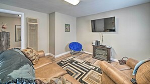 A living room with a sofa, a blue chair, a TV, and a fireplace. - Red Lodge Retreat w/ Yard - Walk to Restaurants! (Red Lodge)