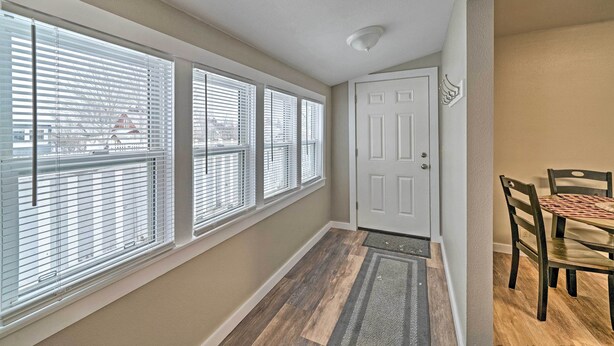 A hallway with large windows, a door, and a dining area with chairs and a table. - Red Lodge Retreat w/ Yard - Walk to Restaurants! (Red Lodge)