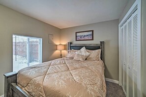 A bedroom with a bed, a nightstand, a lamp, a window with blinds, a framed picture on the wall, and a closet with louvered doors. - Red Lodge Retreat w/ Yard - Walk to Restaurants! (Red Lodge)