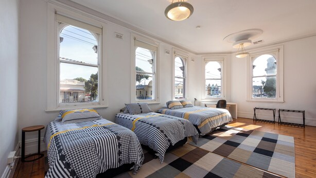 A room with three beds, large windows, a checkered rug, and a desk with a chair. - Private Unit in Heritage Building in Fitzroy North (Fitzroy North)