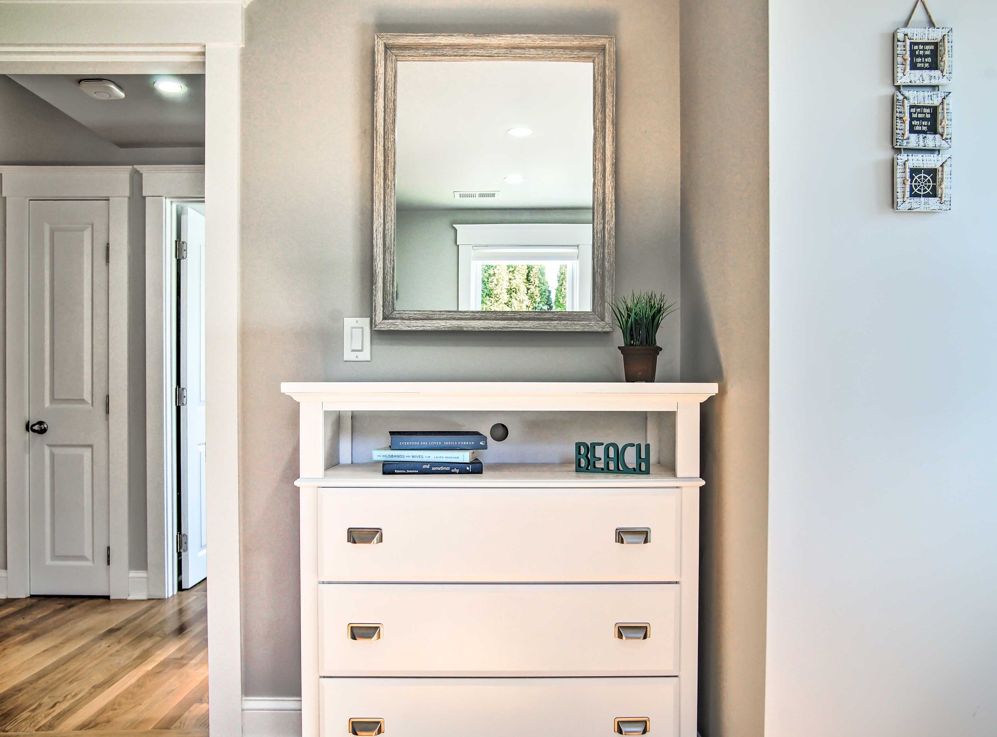 A hallway with a white console table, a mirror, and a small potted plant.
