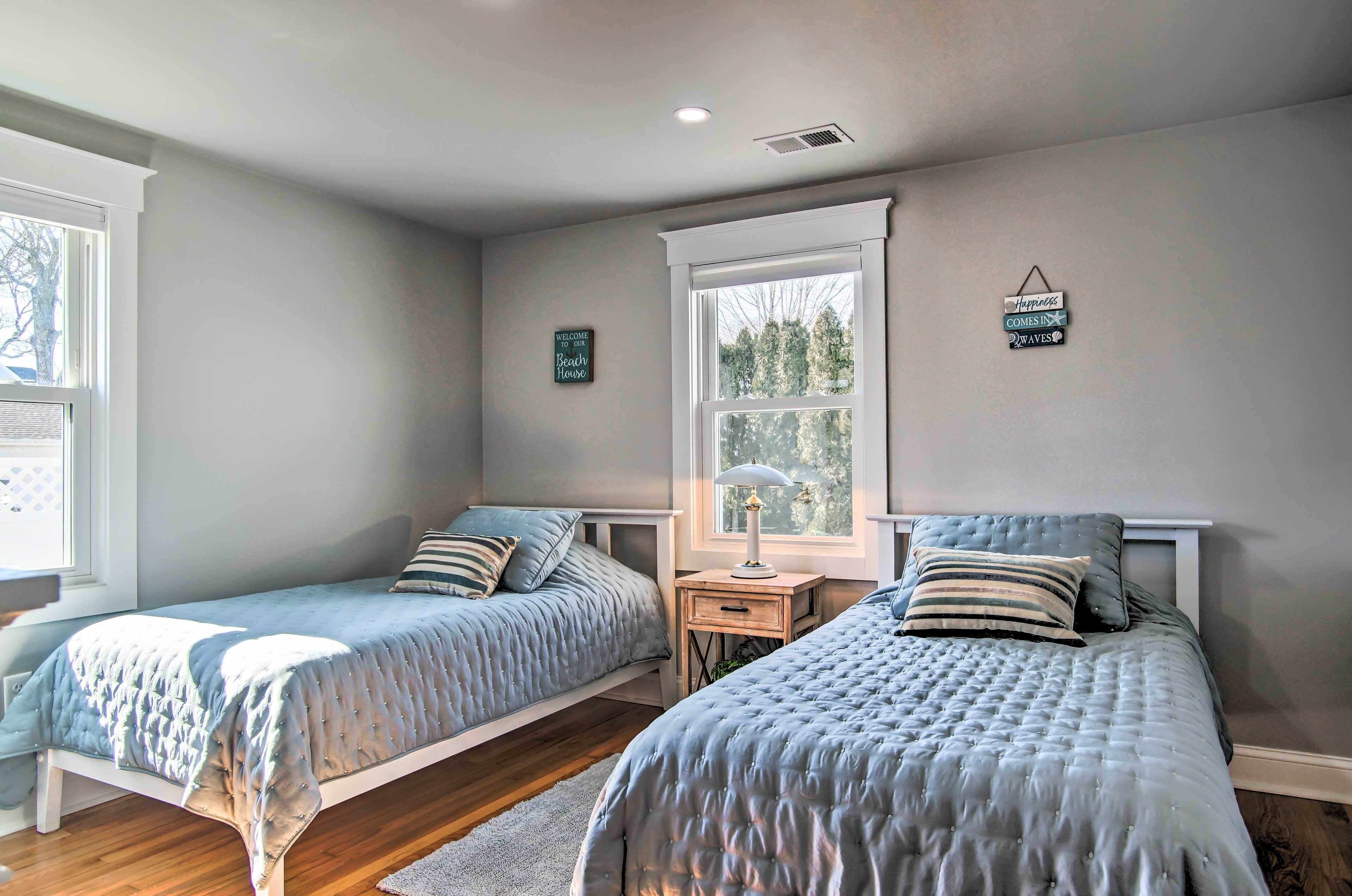 A bedroom with two beds, a nightstand, a window, and a wall-mounted sign.
