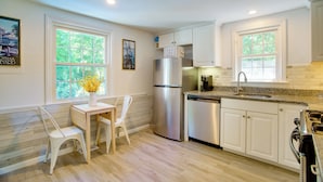 Una cocina moderna con armarios blancos, un refrigerador de acero inoxidable, un lavavajillas y una encimera de granito.