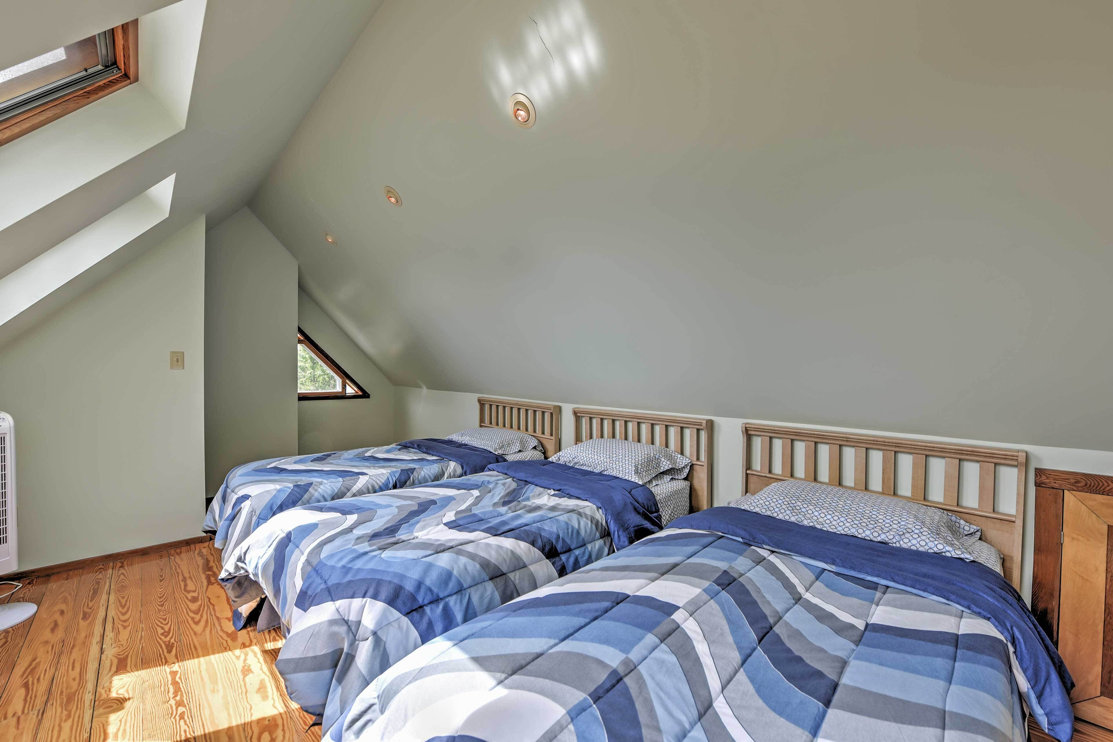 Ein Schlafzimmer mit zwei Betten, Holz-Kopfteilen und einem Dachfenster.