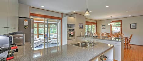 Una cocina moderna con encimeras de granito, electrodomésticos de acero inoxidable y una zona de comedor con sillas de madera.