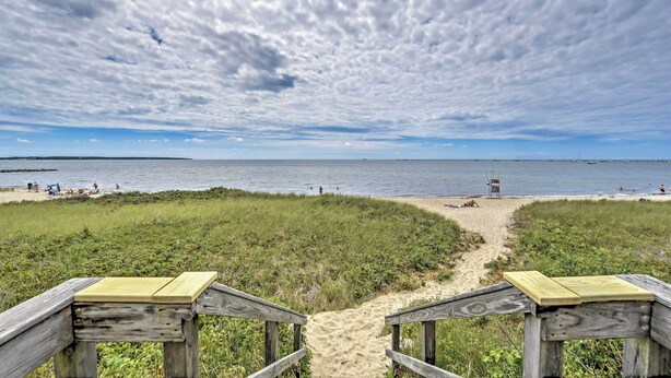 A beach with a wooden walkway leading to the shore, a lifeguard tower, and a clear view of the ocean. - Walk to Beach! Hyannis Family Haven w/ Deck (Hyannis)