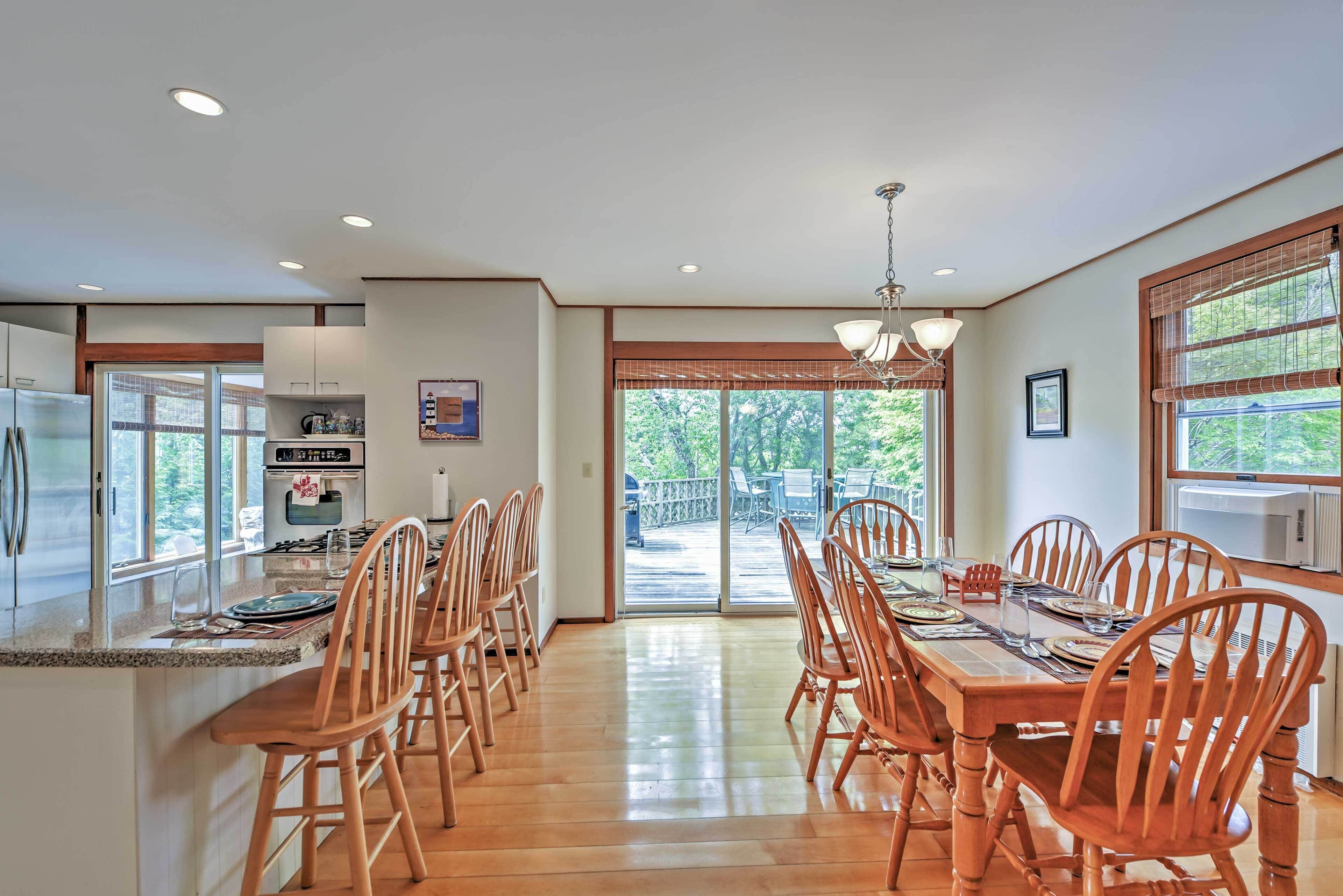 A spacious kitchen with a dining area, wooden chairs, a large island, and a view to the outside.
