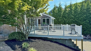 A house with a covered deck, outdoor seating, and a view of a forested area. - Walk to Beach! Hyannis Family Haven w/ Deck (Hyannis)