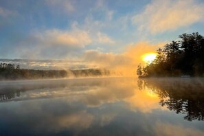 Un lago tranquilo que refleja árboles y un cielo despejado.