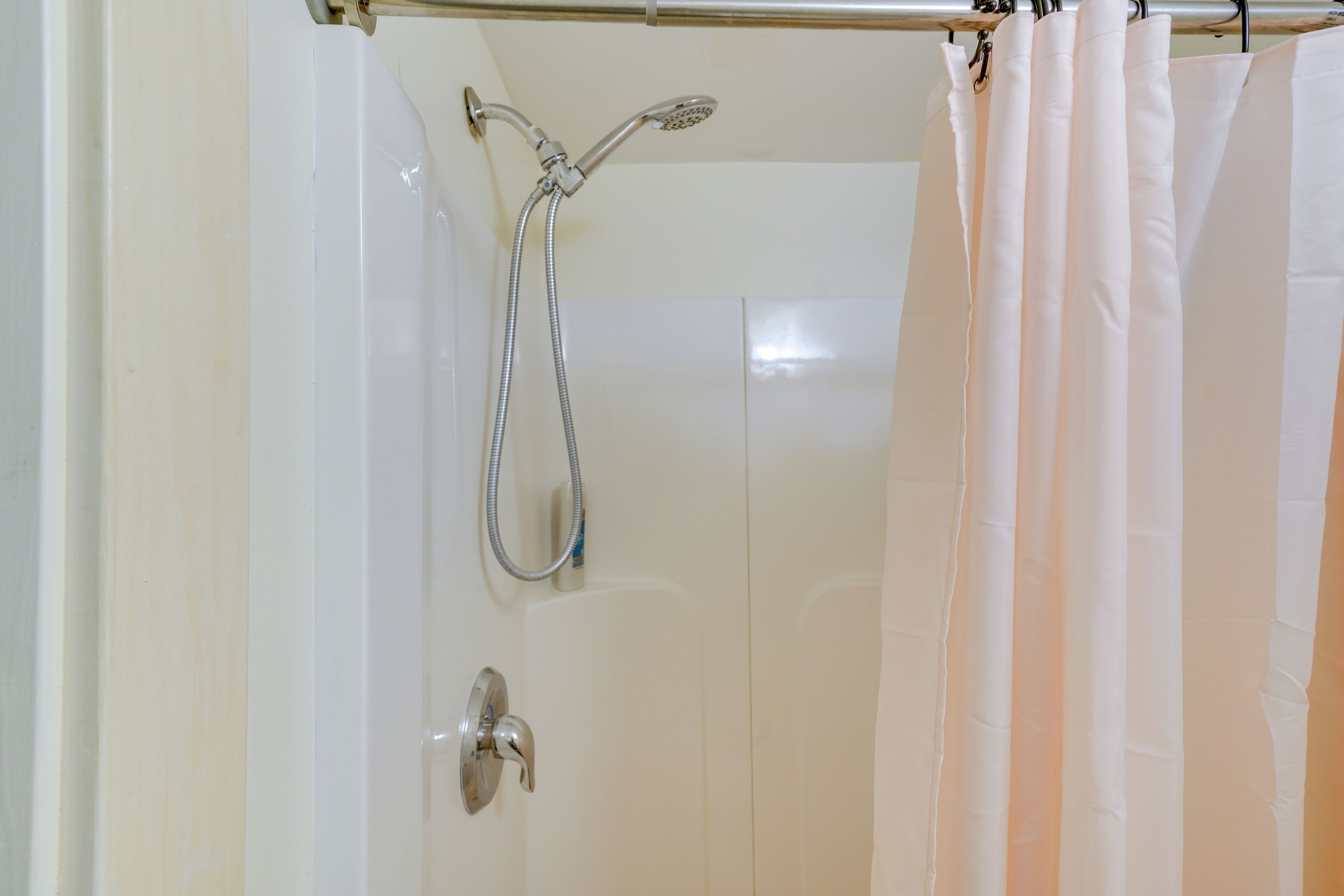 A shower area with a showerhead and hose, a curtain, and a door.