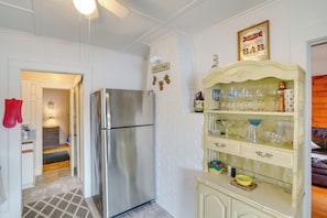 Una cocina con refrigerador de acero inoxidable, pared de ladrillo blanco y una zona de bar con cristalería.