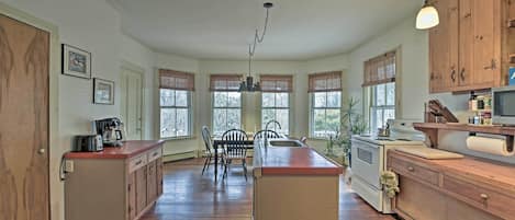 A spacious kitchen with wooden cabinets, a central island, and a dining area with chairs.