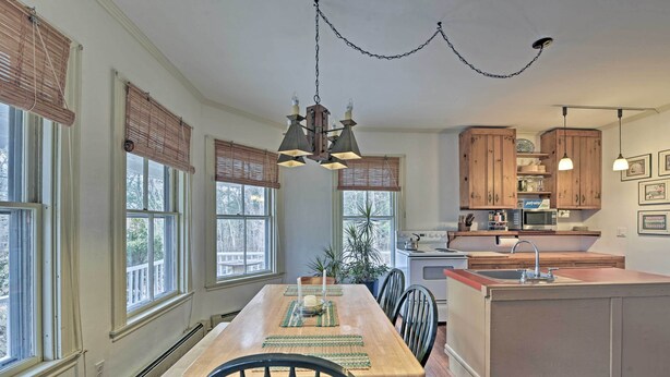 A kitchen with wooden cabinets, a dining table with chairs, and a hanging light fixture. - Easy Access to Beaches: Vineyard Haven House (Vineyard Haven)