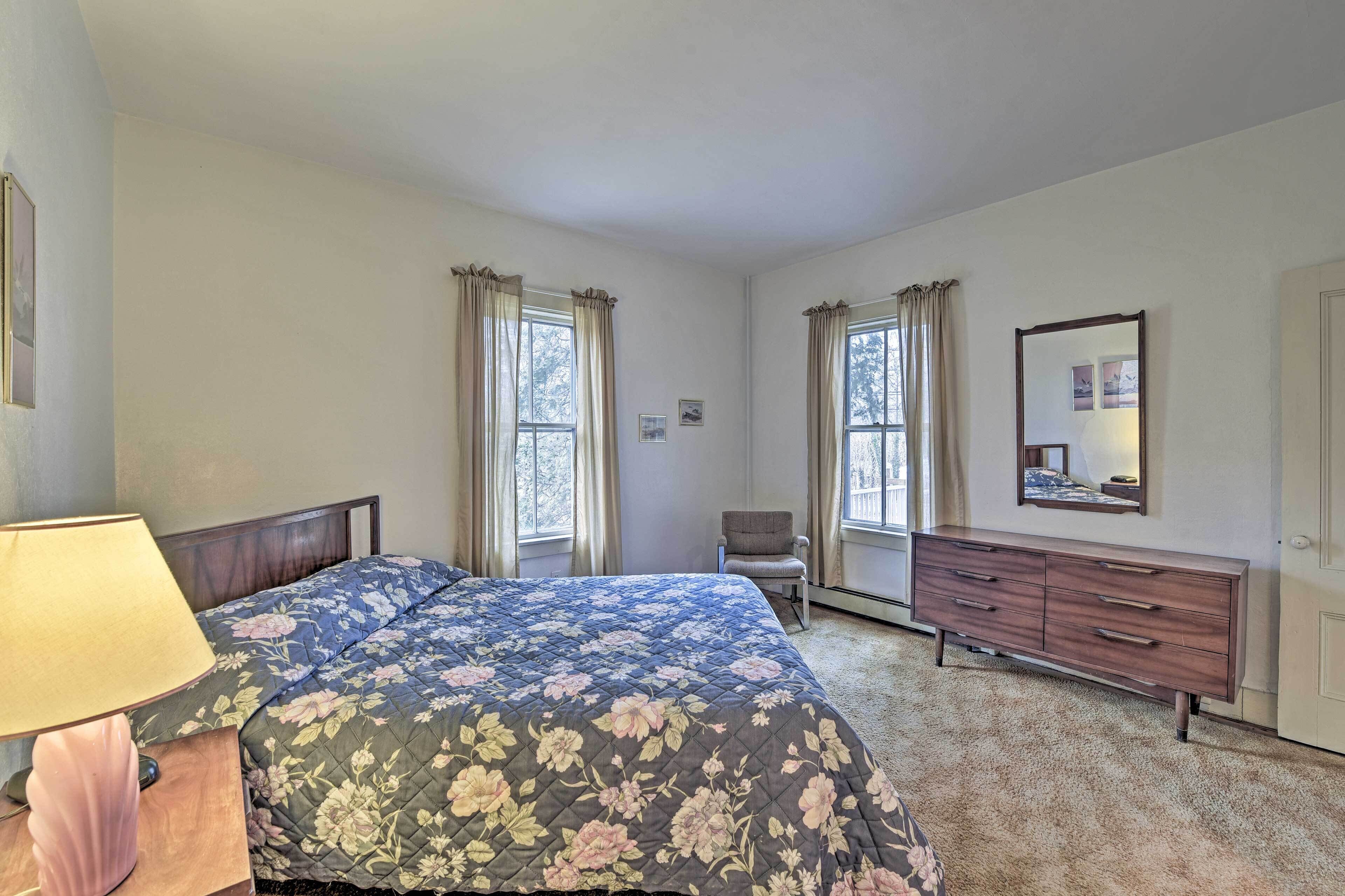 Une chambre à coucher avec un lit, une commode, une chaise et une fenêtre.