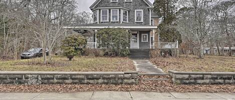 A two-story house with a front porch, a small front yard, and a driveway leading to the front door.