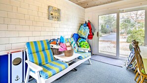 A cozy room with a striped sofa, a small table, and a view of the outdoors. - 2 Mi to Shore: Home w/ BBQ & Beach Gear in Mashpee (Mashpee)